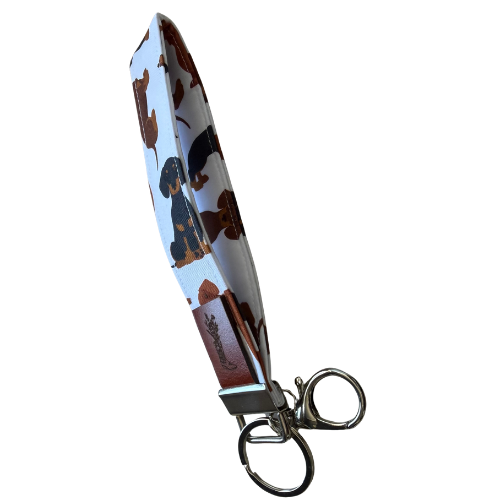 A fabric keychain pouch with a dachshund pattern, featuring a silver metal key ring and clasp, shown on a plain white background.