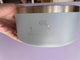 Light blue container with gold lid held by a hand against a purple background