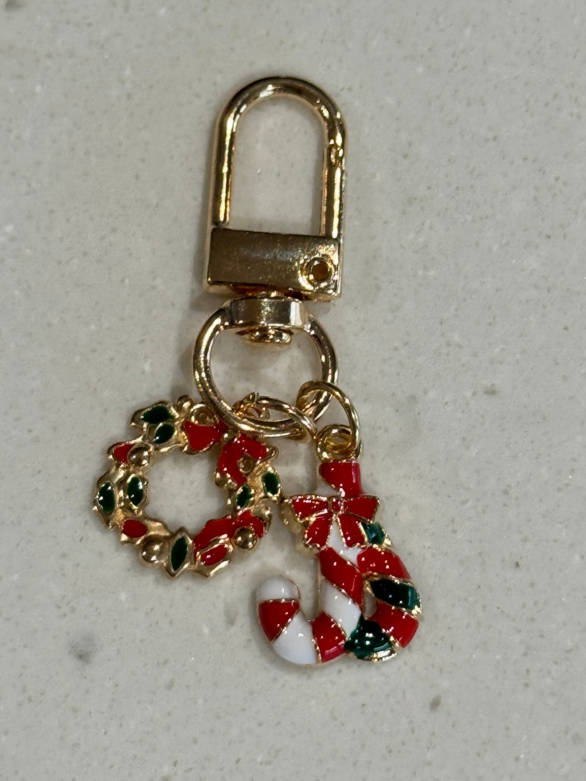 Christmas-themed keychain with candy cane and wreath design on a gray background